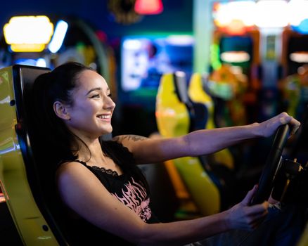 Woman smiling while playing a racing game at an indoor arcade.