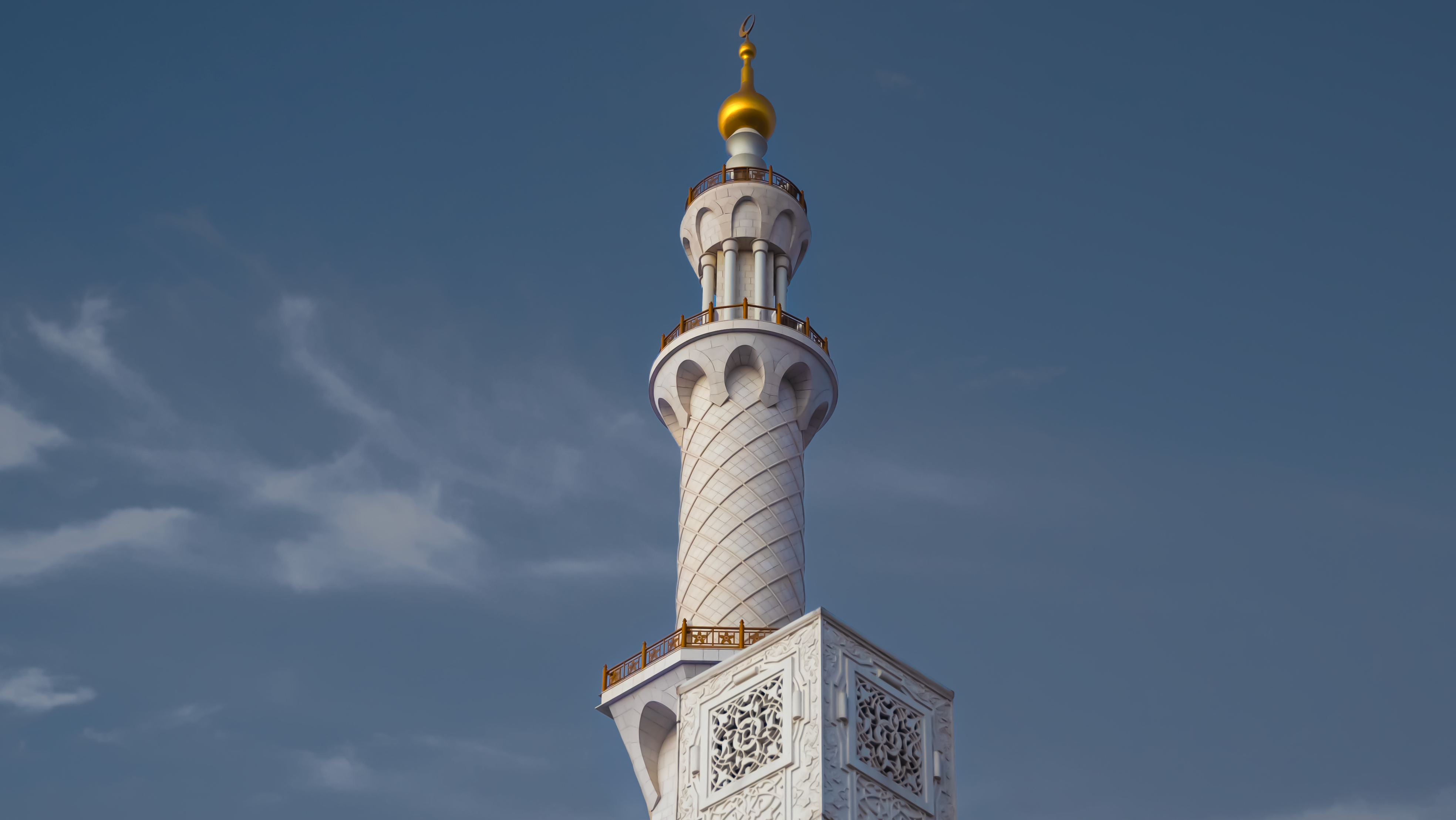 Close-up view of a minaret at Sheikh Zayed Grand Mosque, showcasing intricate Islamic architecture under a clear blue sky.