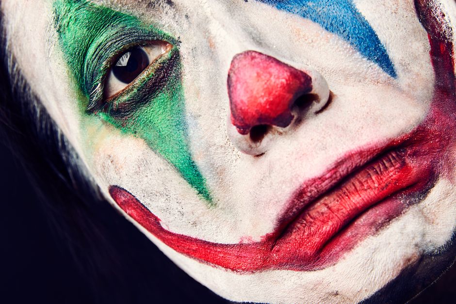 Vivid close-up of a clown face with colorful makeup depicting an emotional expression.