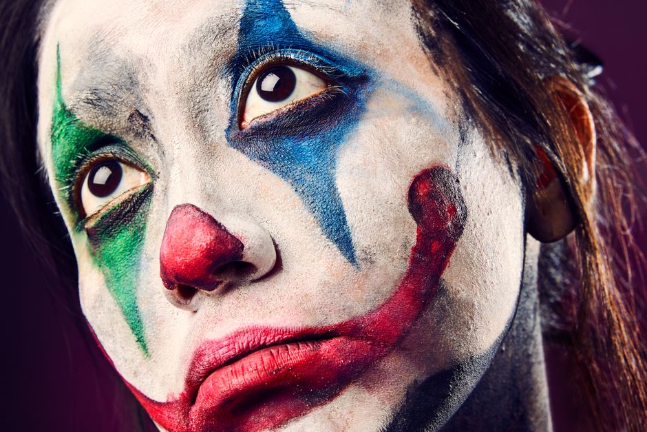 Detailed close-up portrait of a clown with colorful face paint, expressive eyes, and dramatic makeup.