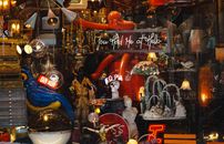 An eclectic display of antiques in a shop window featuring neon signs and retro decor.