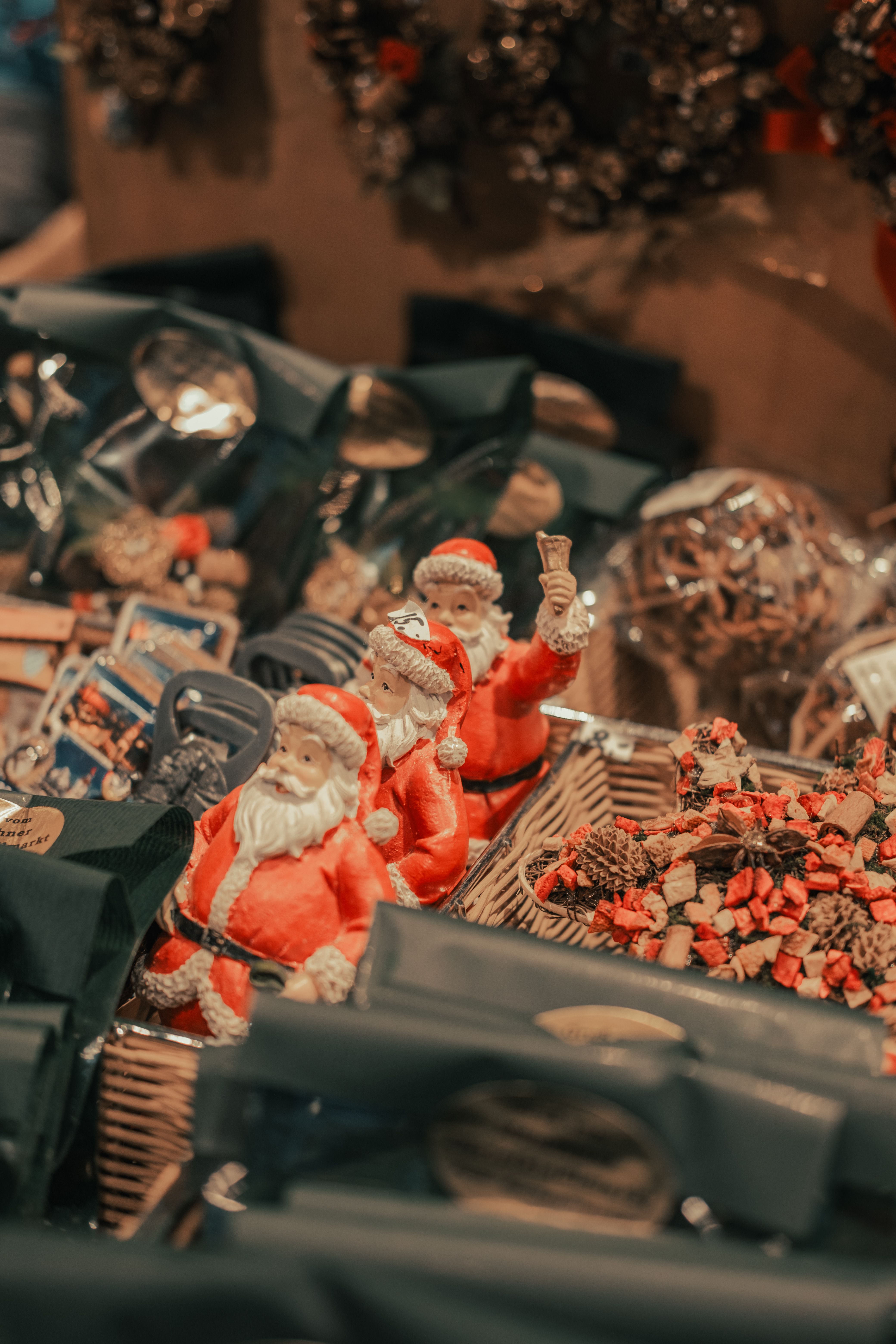 A warm and festive display featuring Santa Claus figurines surrounded by Christmas gifts and decorations.