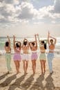 六名穿着五颜六色运动服的妇女在阳光明媚的海滩上一起伸展