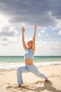 一个女人在阳光明媚的海滩上，正以瑜伽姿势向天空伸展