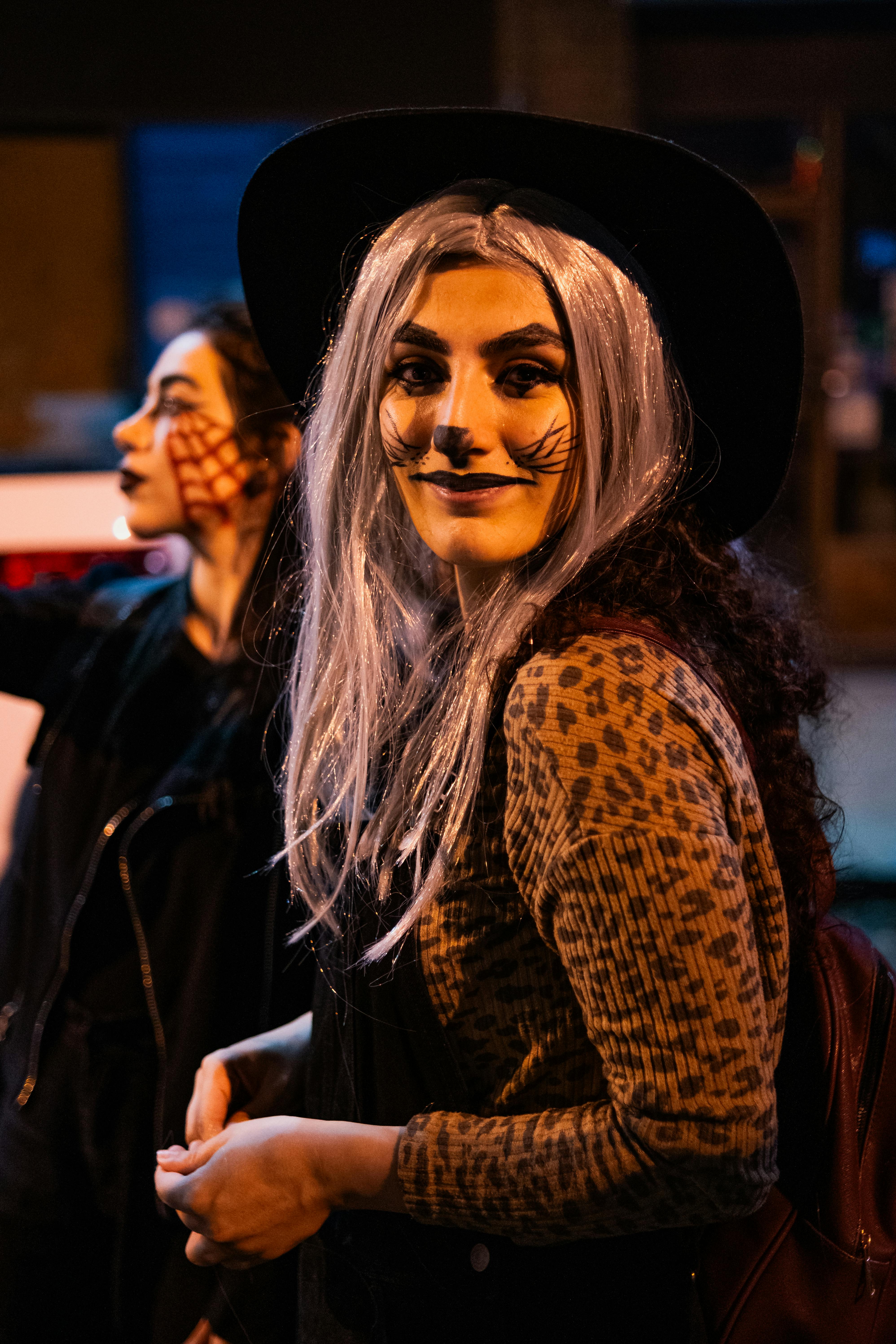 Two women in creative Halloween costumes on a lively street in Toronto at night.