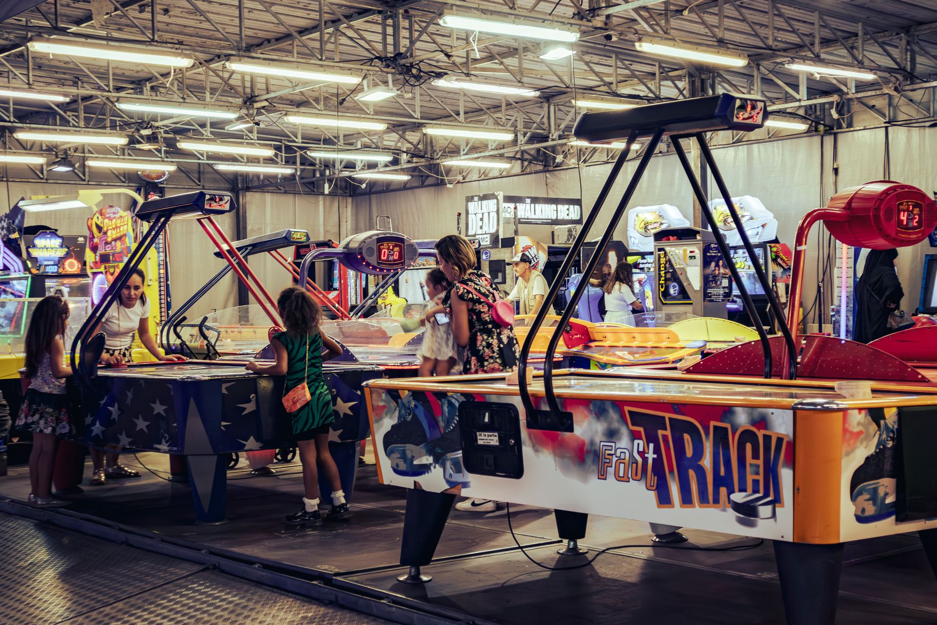 Children and adults enjoy air hockey games in a lively indoor arcade setting.