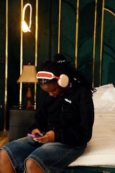 Teenager engrossed in music, wearing headphones, sitting indoors in Abuja, Nigeria.