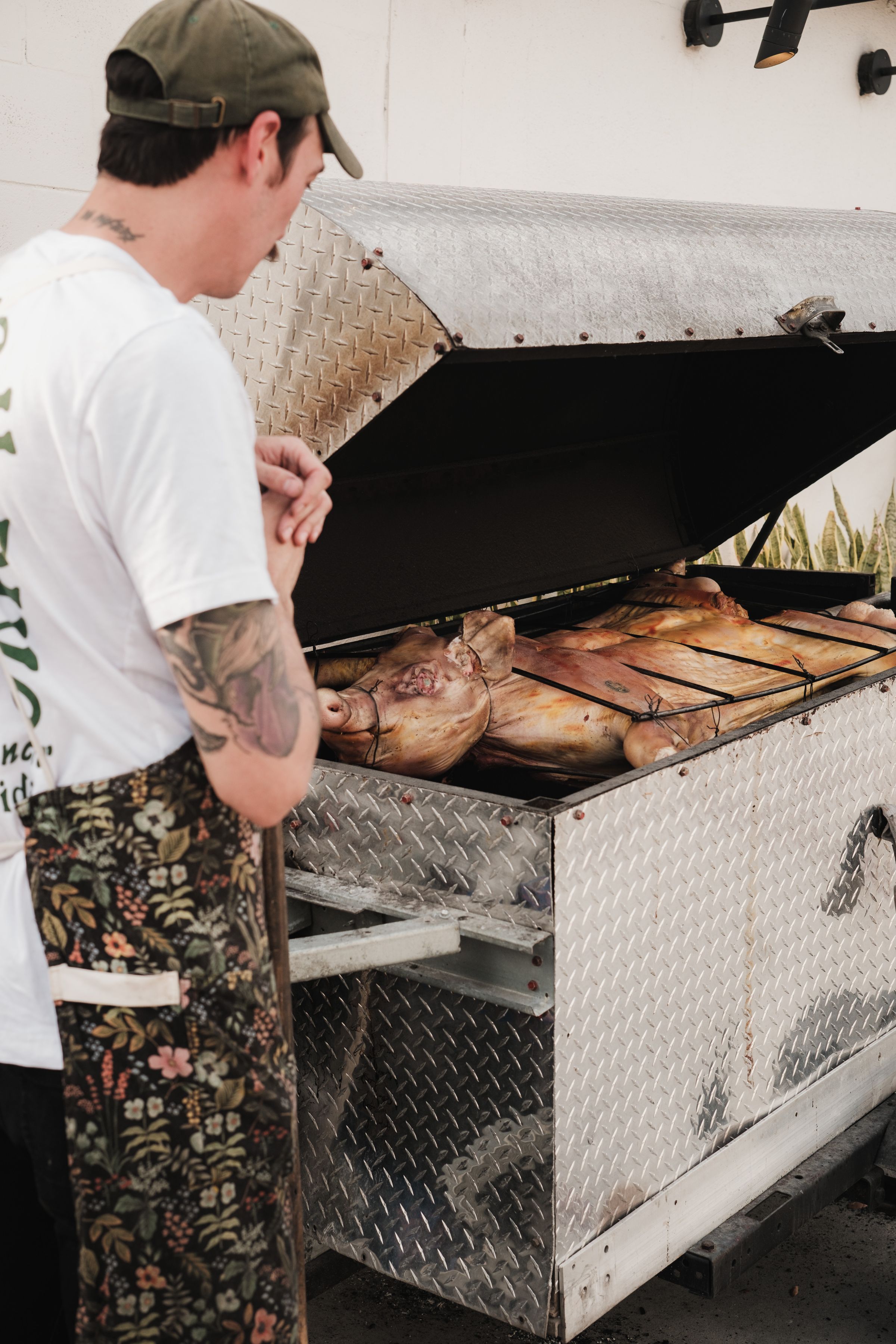 A pig roasting slowly over an open fire, tended by hand