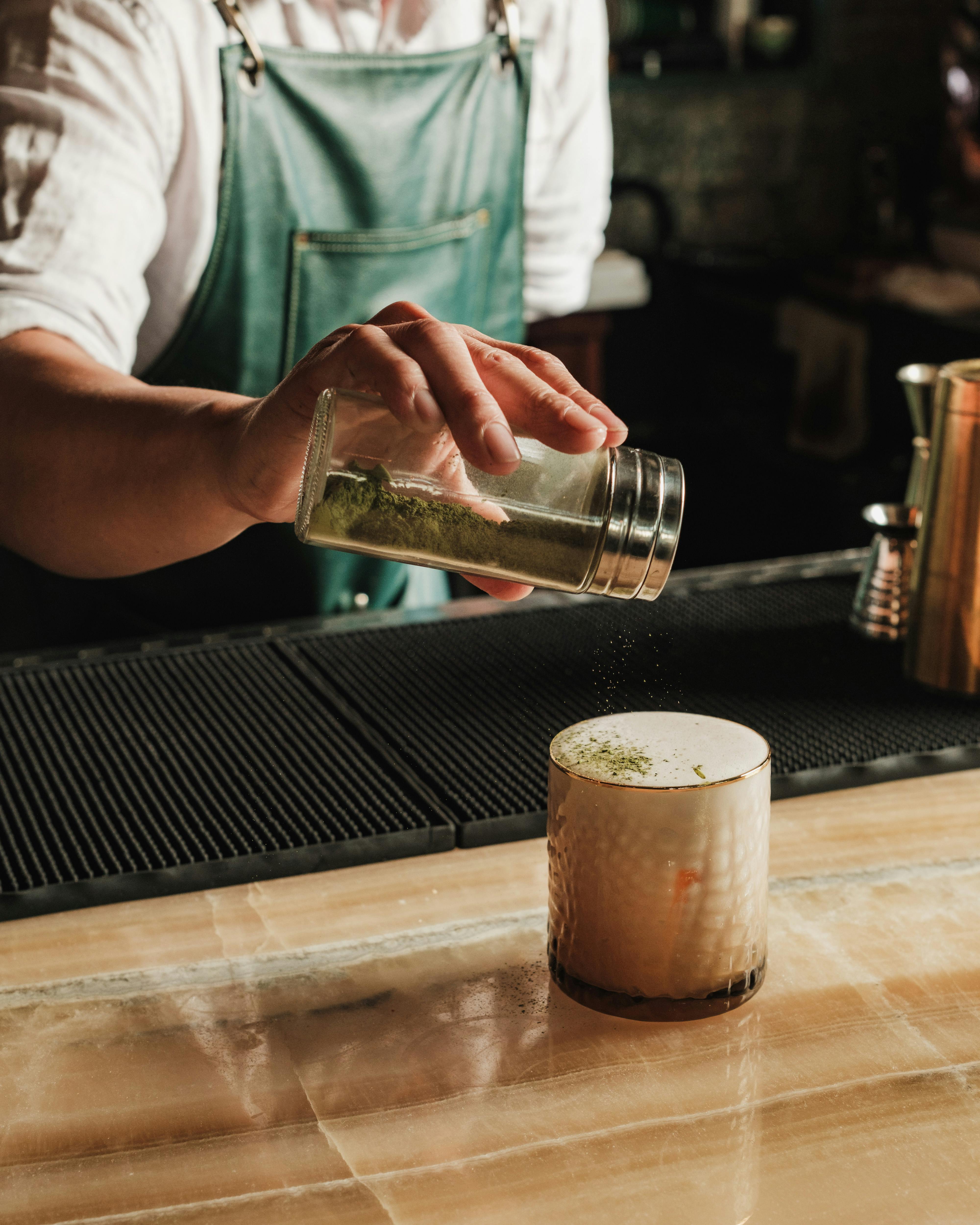 bartender sprinkling spices on a cockail