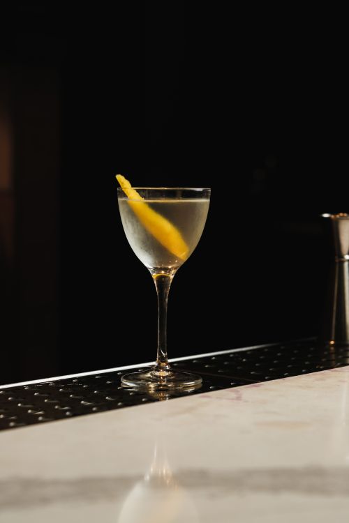 Free A sophisticated martini with a lemon twist on a dimly lit bar counter. Stock Photo