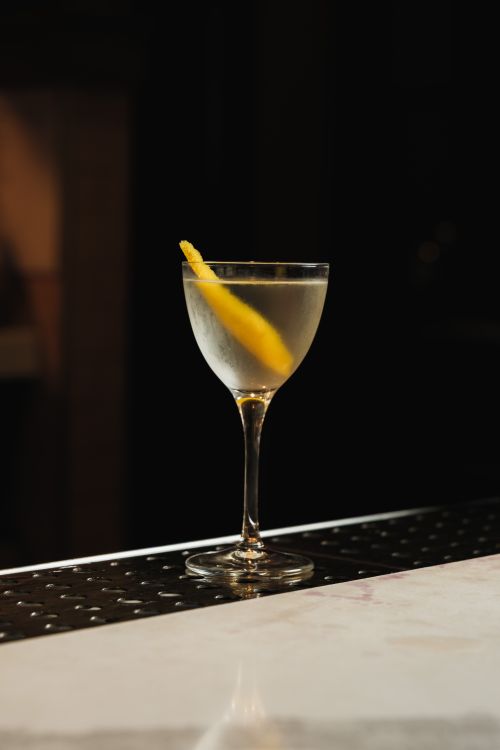 Free A classic martini with a lemon twist sits elegantly on a marble bar counter. Stock Photo