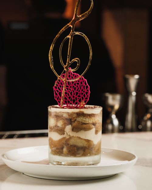 Free Delicious tiramisu dessert topped with a creative sugar sculpture on a white plate. Stock Photo