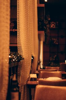 A warmly lit cozy restaurant interior with elegant curtains and comfortable seating.