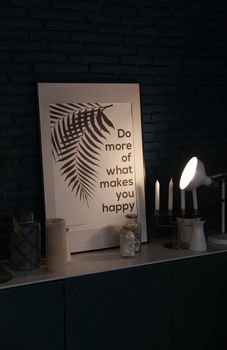 Framed wall art with fern leaves and motivational quote illuminated by a lamp.