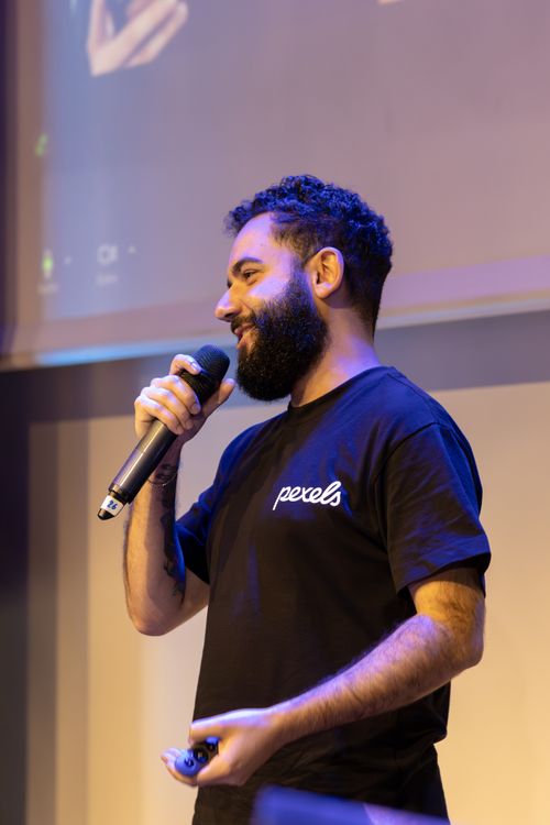 Man speaking at an indoor event with a microphone