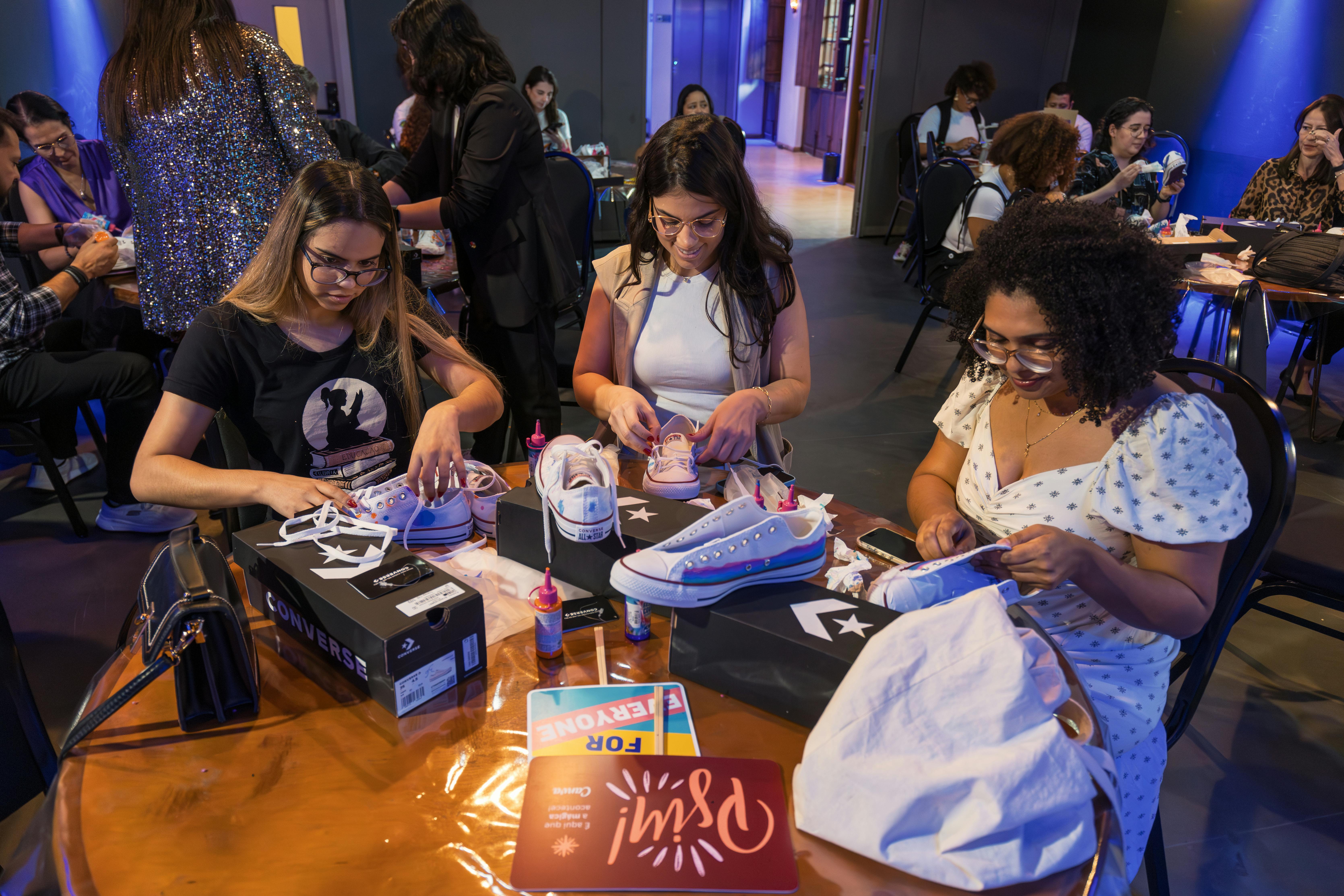 Gratis Le donne personalizzano le scarpe Converse durante un workshop creativo al chiuso. Foto a disposizione