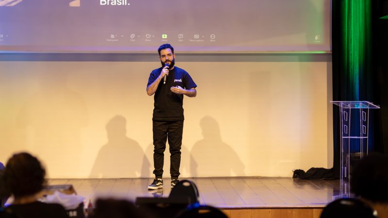 Man speaking on stage with a microphone at a conference in Brazil.