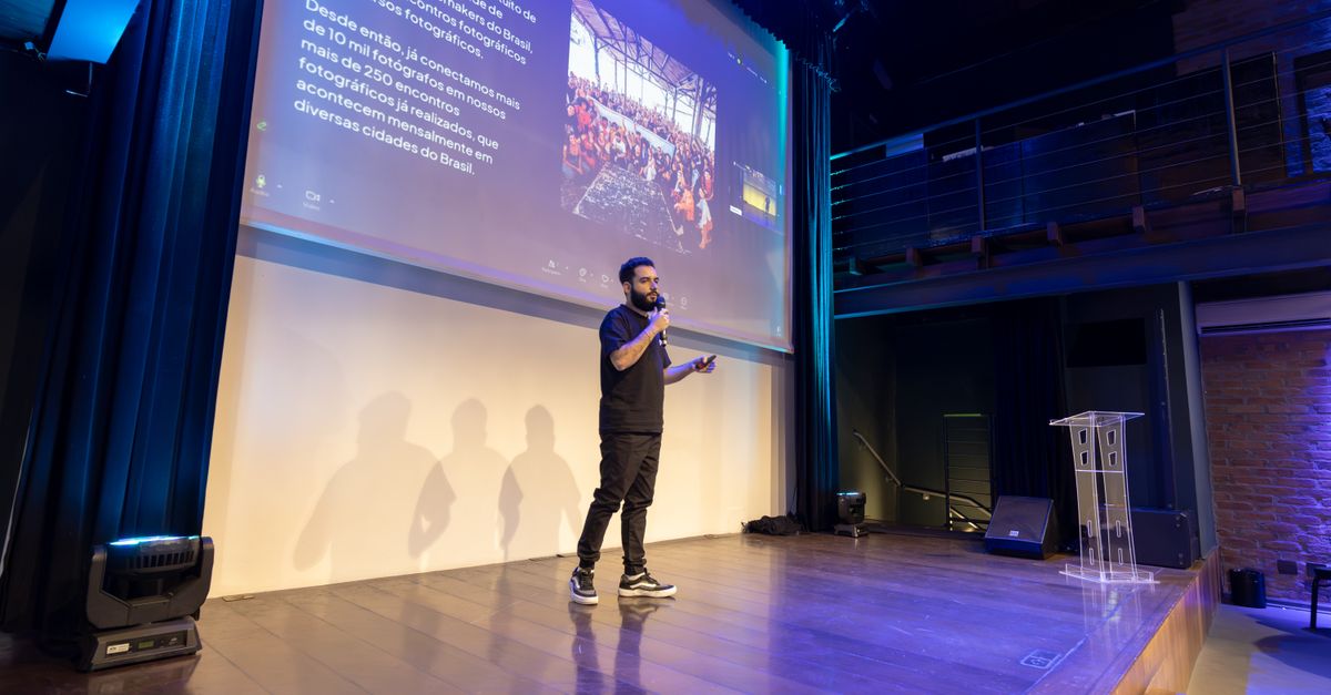 Speaker presenting at a conference with a projected presentation slide on screen.