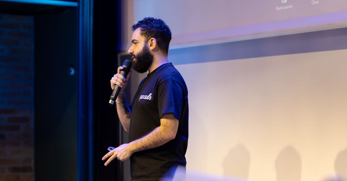 Man speaking into microphone during a presentation indoors.