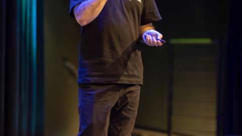 A man speaks confidently on stage, highlighting a professional presentation.