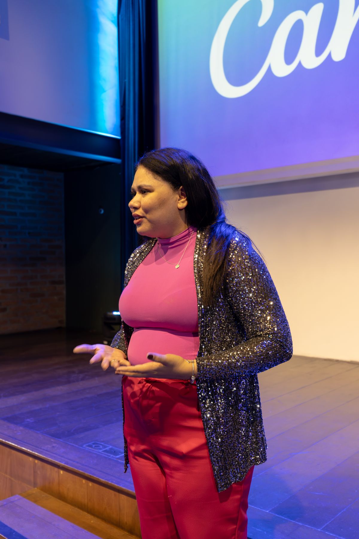 Mulher apresentando palestra em palco com iluminação de evento