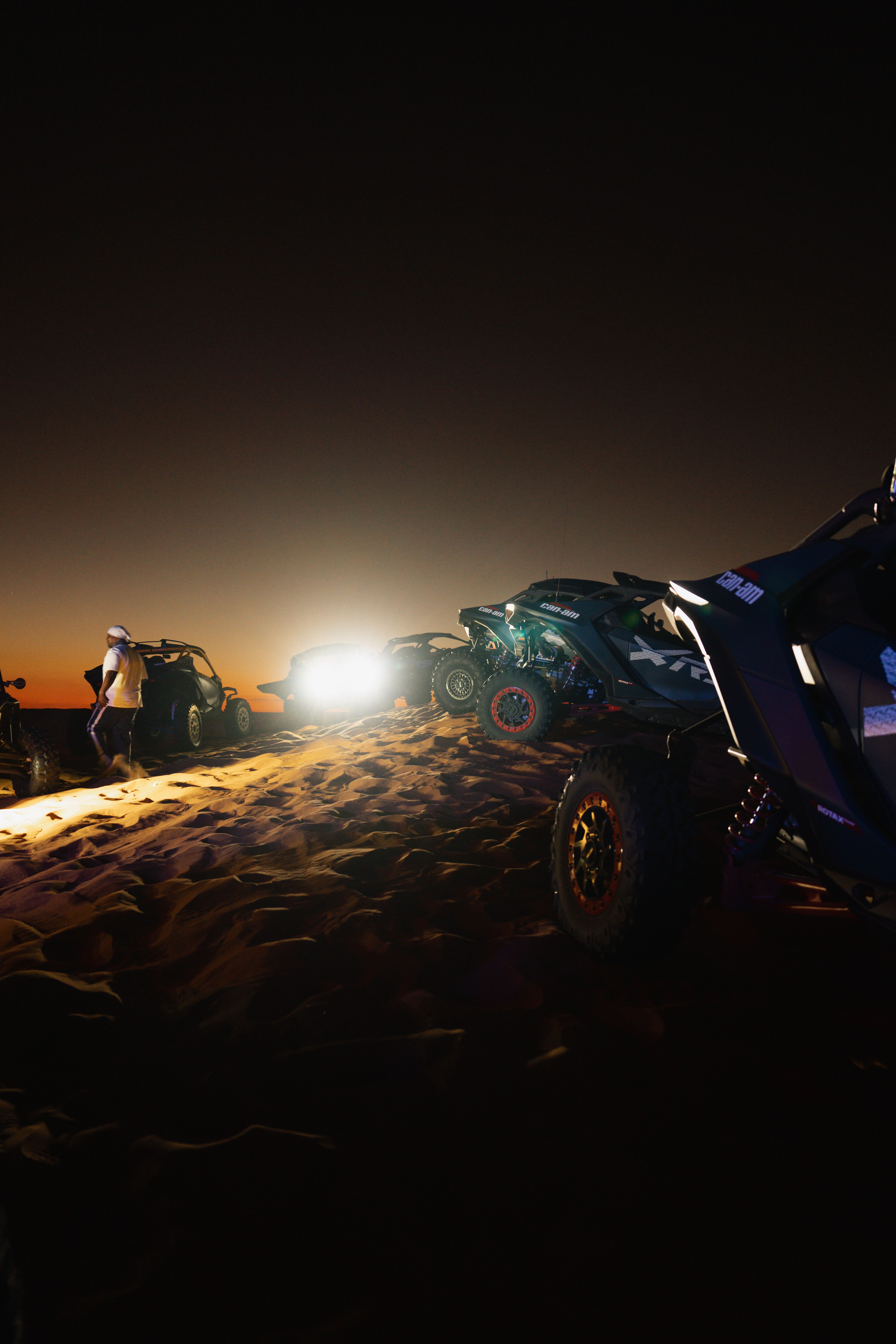ATVs on Dubai desert dunes under starry night sky, showcasing thrill and adventure.