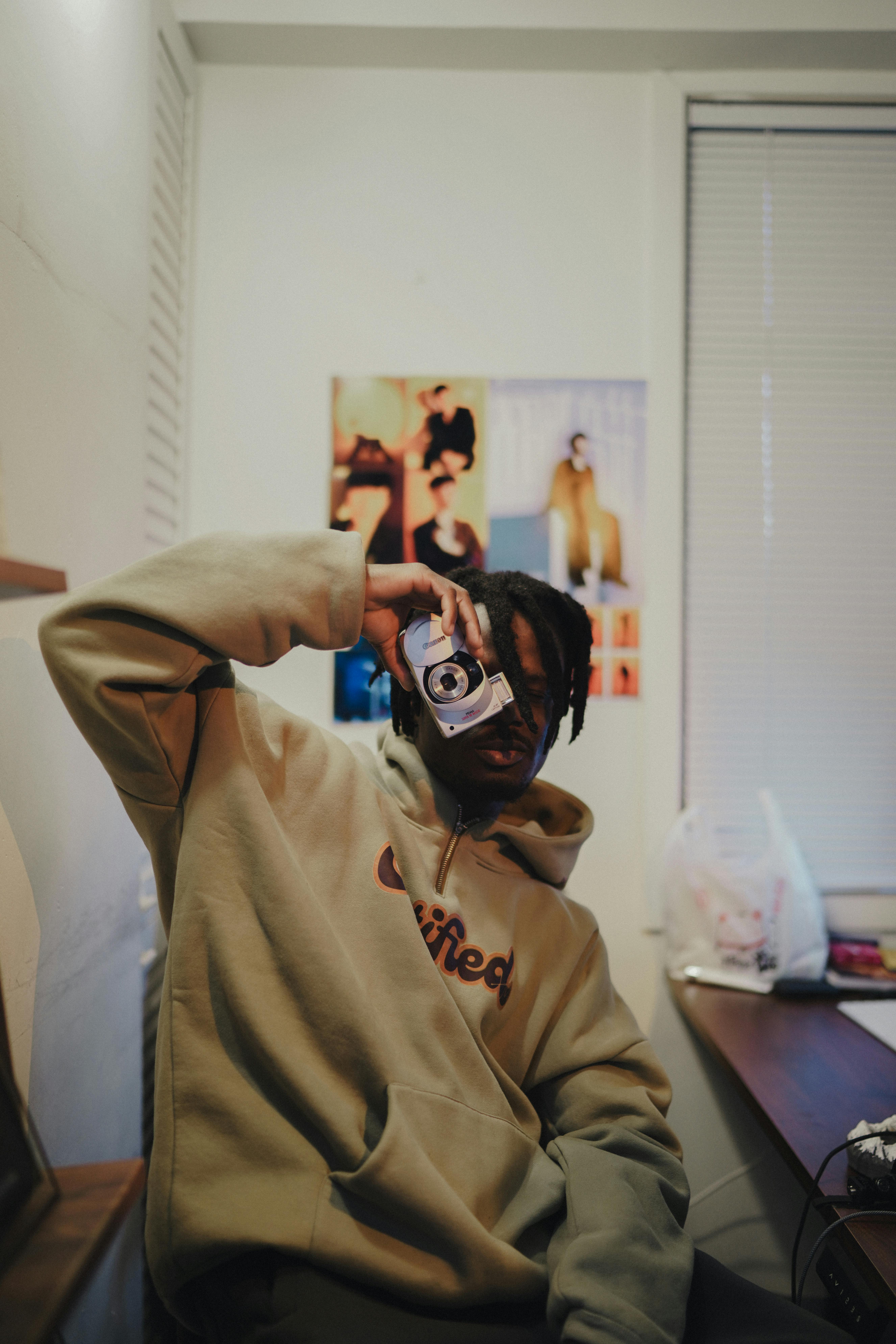 A young adult posing with a vintage camera in a cozy art studio setting.