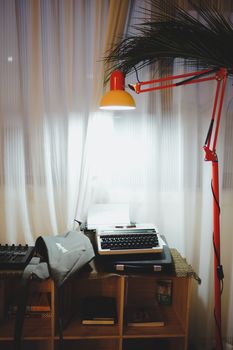 A stylish setup with a vintage typewriter and modern lamp in a cozy room.