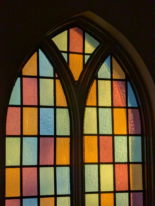 Free Vibrant stained glass windows casting colorful light patterns in church interior. Stock Photo