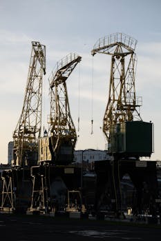 Silhouetted industrial cranes at a port during sunset, showcasing urban infrastructure.