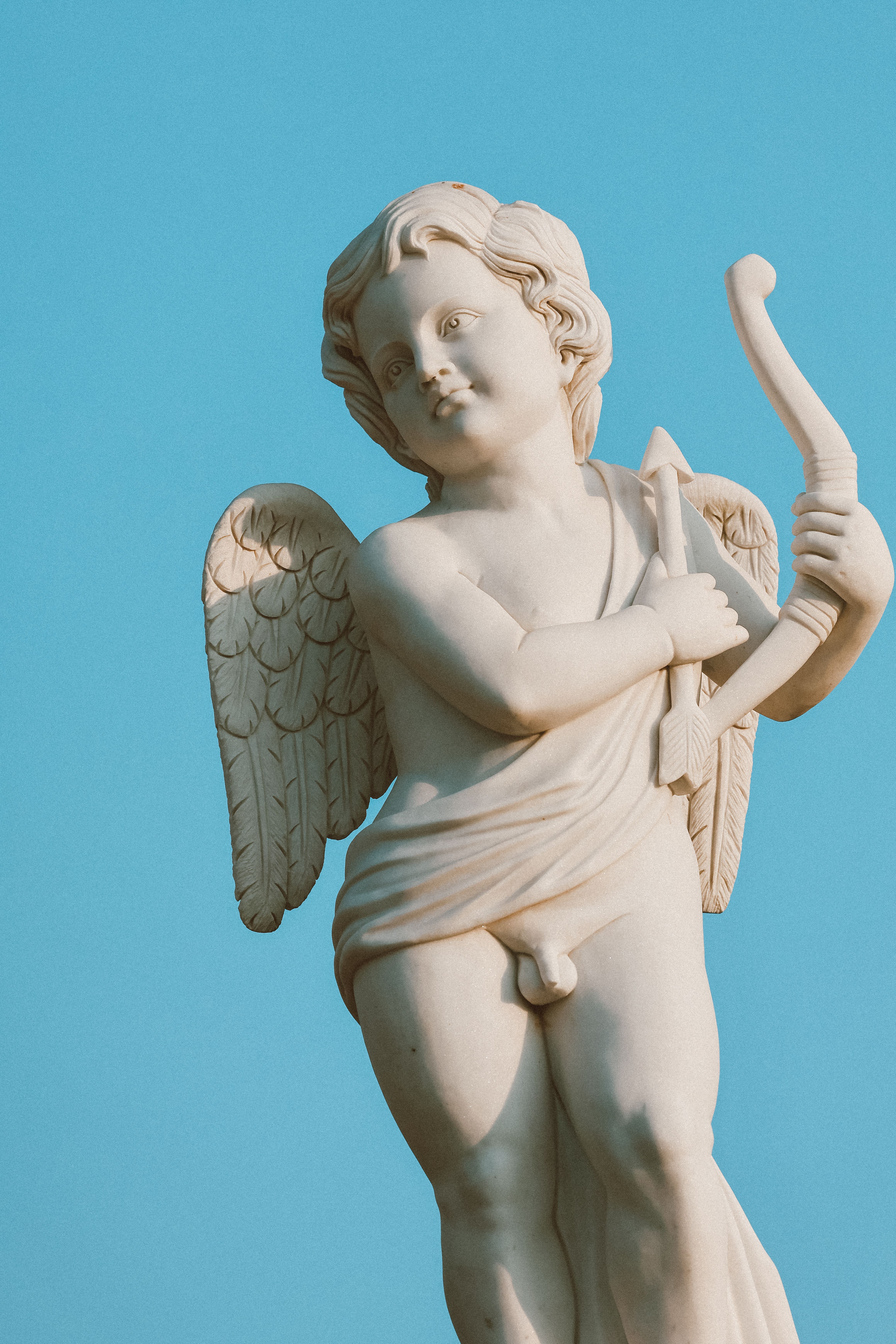 Renaissance Cupid Sculpture with Bow against Blue Sky · Free Stock Photo