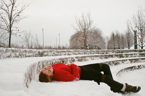 Frau, Die Roten Pullover Trägt, Der Auf Schneebedecktem Boden Liegt