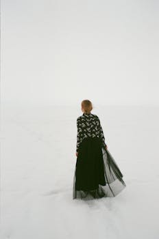 一名身穿黑色连衣裙的女子，站在广阔的雪景中，令人感到孤独