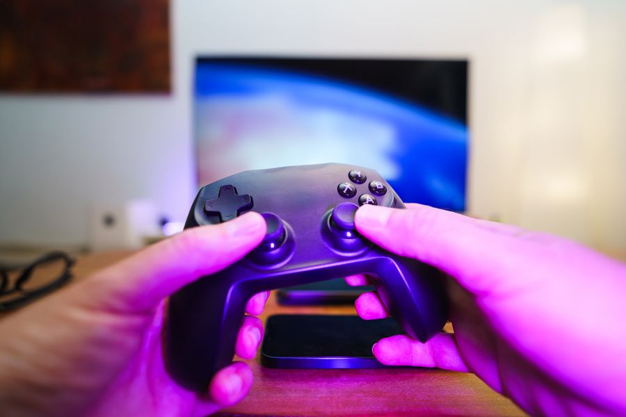 Hands holding a game controller in front of a TV screen