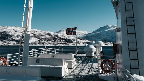 Free Scenic view of a ship deck with a Norwegian flag and snowy mountains in winter. Stock Photo