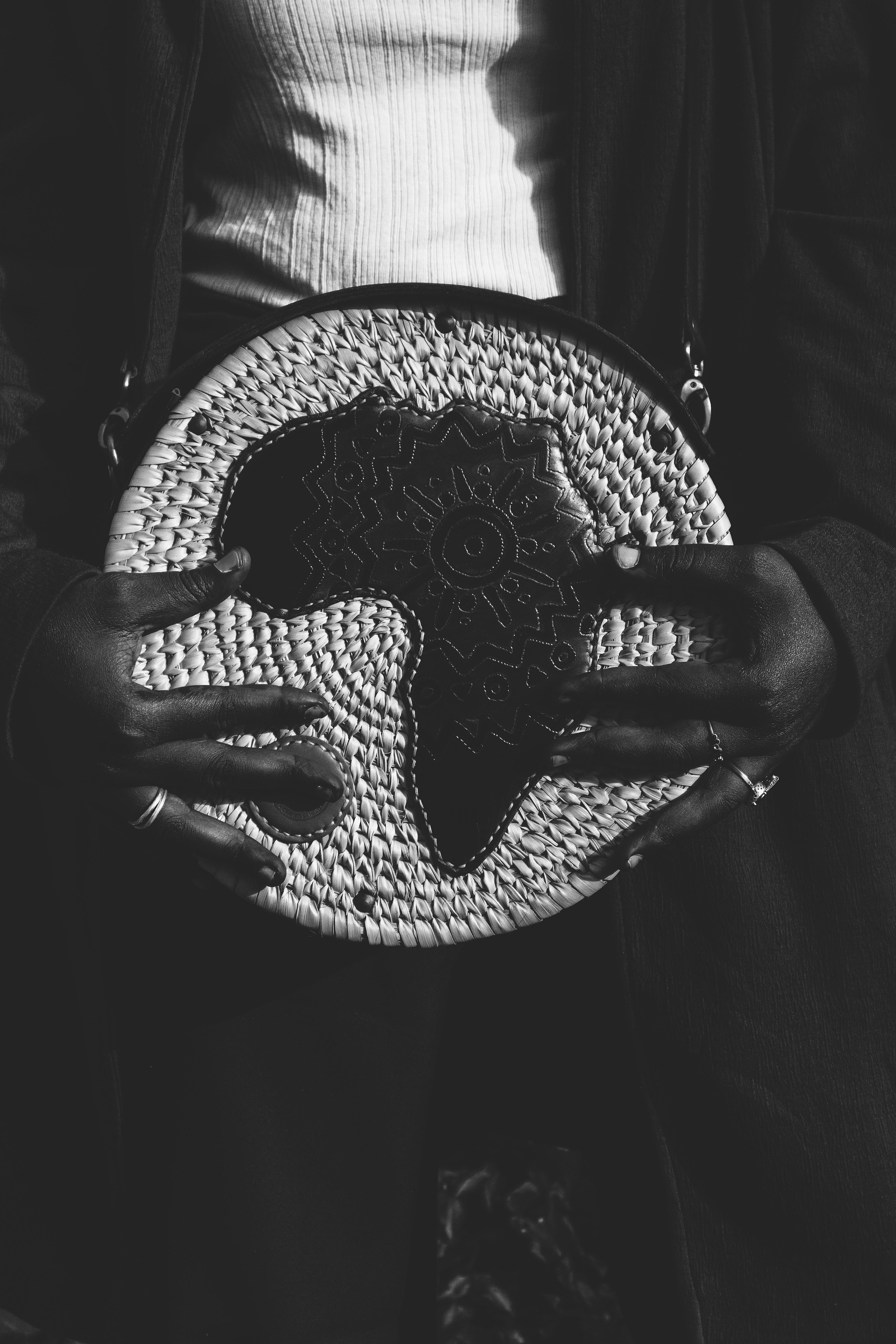 Gratuit Gros plan noir et blanc de mains tenant un sac à main tissé à thème africain. Photos