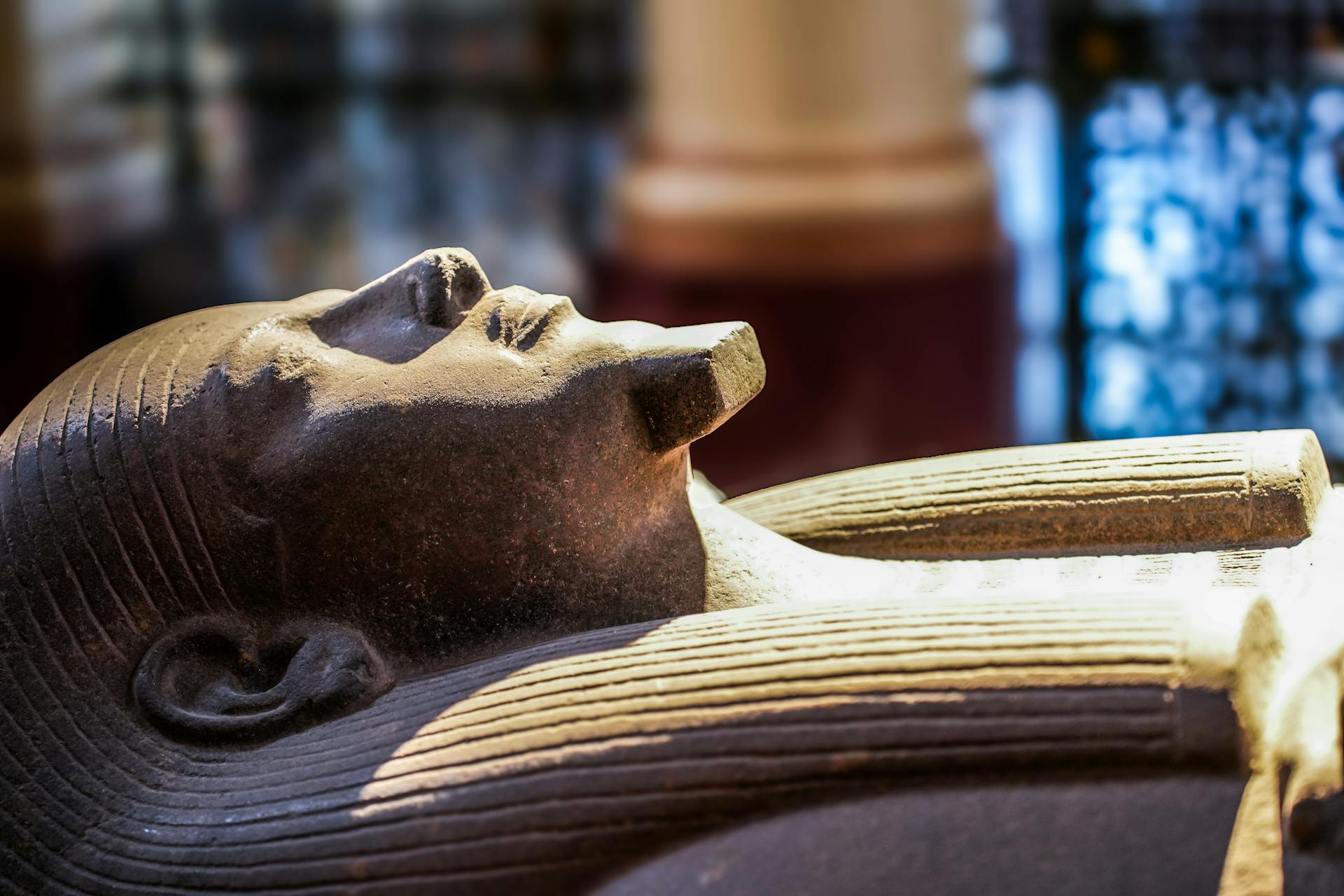 Close-up of an ancient Egyptian sarcophagus on display in a museum, showcasing intricate details.