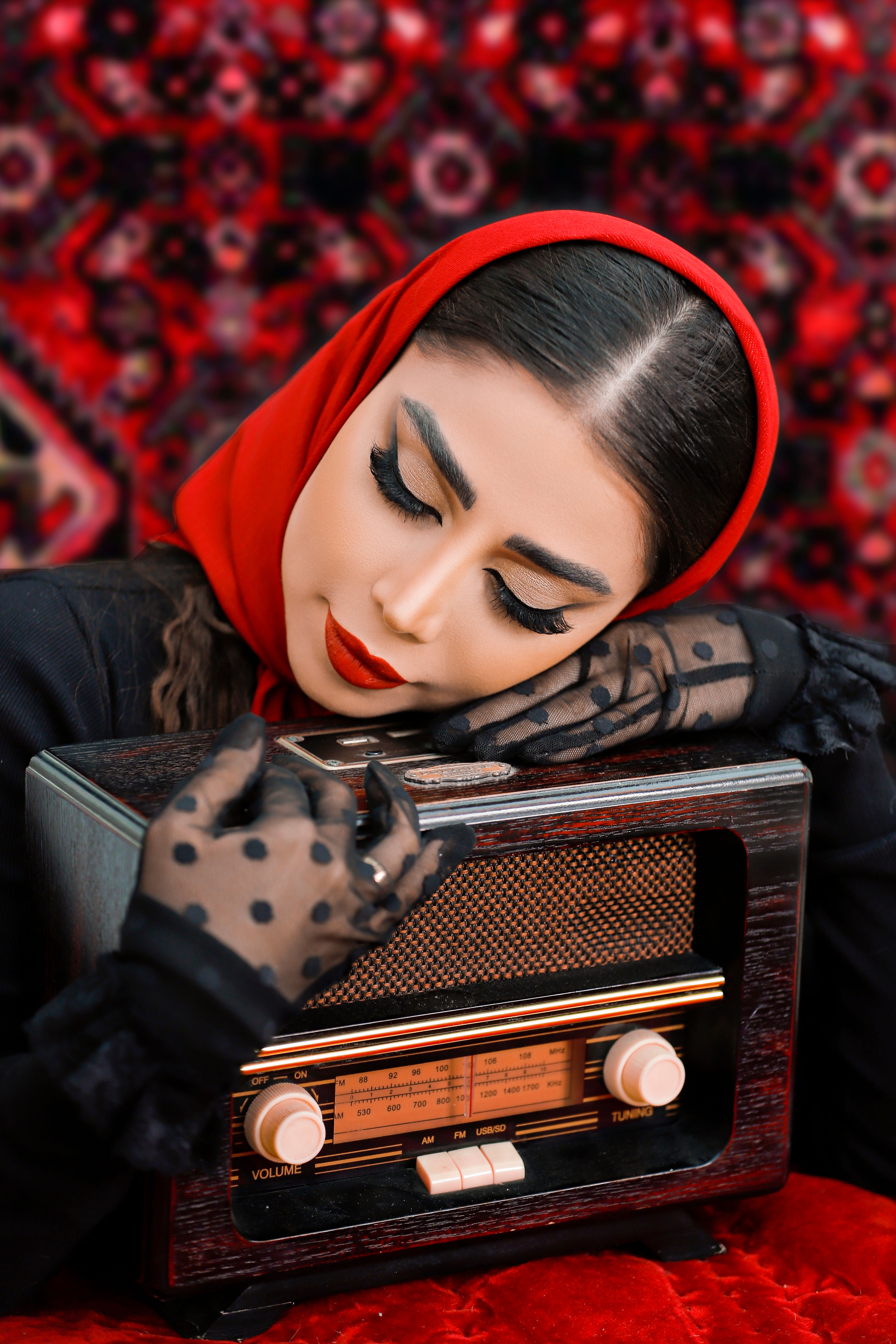 Middle Eastern woman in red scarf gently holding a vintage radio. Vibrant colors and classic style.