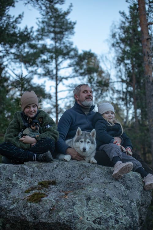 Free A family enjoying the outdoors with a husky and pets, sitting on a rock. Stock Photo