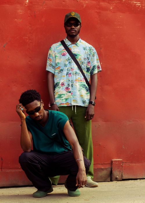 Free Stylish African men posing in street fashion against a red wall. Stock Photo