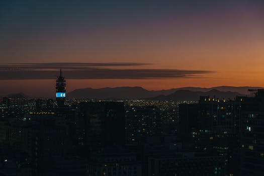 Stunning twilight view of Santiago's skyline with silhouetted skyscrapers and mountains in the horizon.