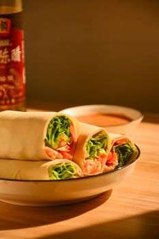 Delicious fresh spring rolls with lettuce and shrimp on a wooden table.
