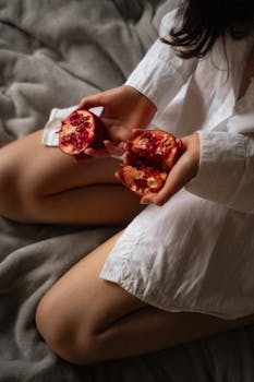 Intimate close-up of a person holding a cut pomegranate, perfect for lifestyle themes.
