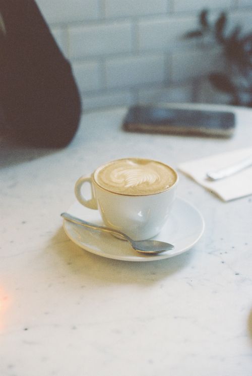 Free Warm café atmosphere featuring a cappuccino on a white marble table, perfect for cozy mornings. Stock Photo
