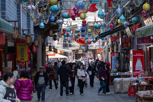 Vibrant market street adorned with colorful lanterns and bustling with people, capturing a lively cultural scene.
