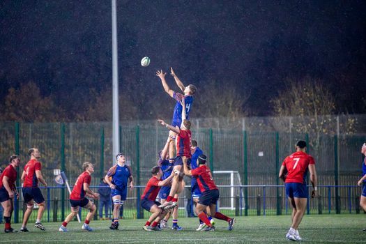 Rugby players compete in a lineout during a match in England, captured on a rainy night., free online jigsaw puzzle on JigsawPuzzlesFreeOnline.org
