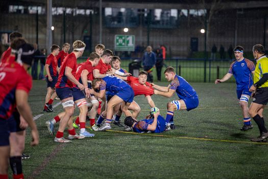 Dynamic scene of rugby players in action on an outdoor field in England.