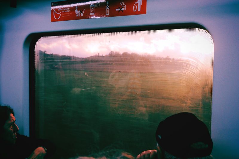 Passenger view from a train window in Barcelona, capturing scenic landscapes at sunset.