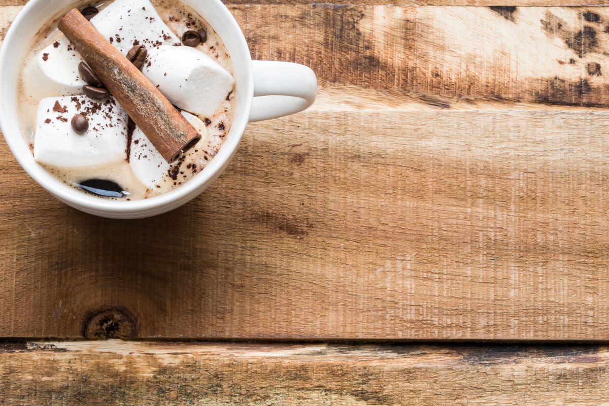 A cozy mug of hot chocolate topped with marshmallows and cinnamon on a rustic wooden backdrop.