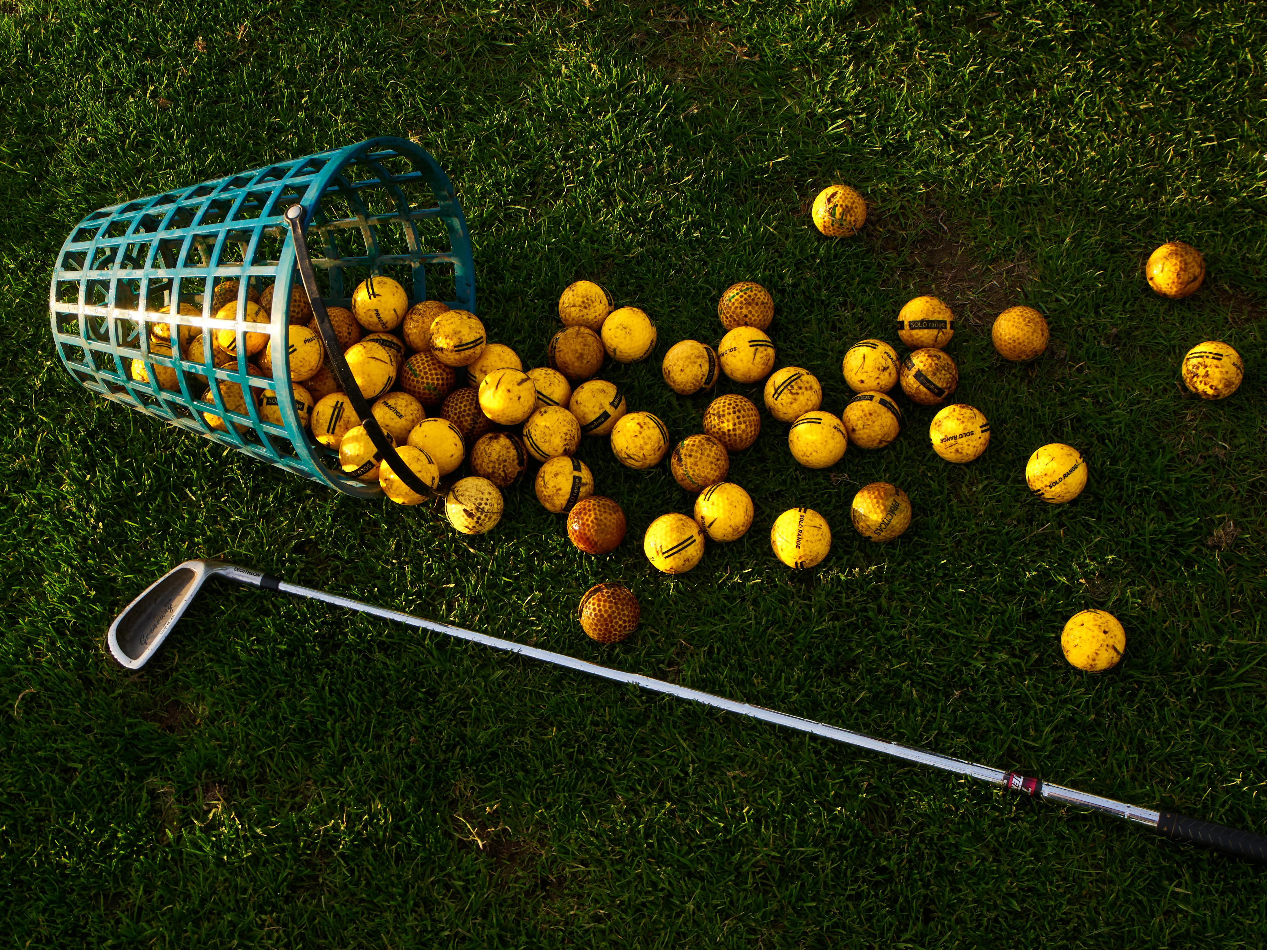 golf balls spilled from basket on green grass